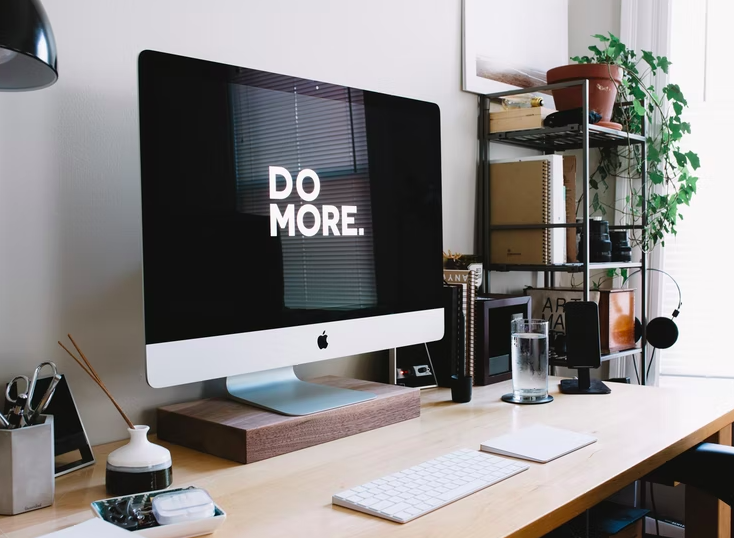 Computer monitor screen on a desk reads "do more"