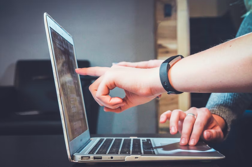 Someone pointing to a lapstop screen to show something to a colleague