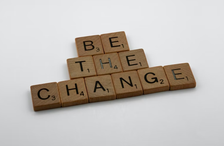 Wooden scrabble tiles spell out the CSR message "Be the change"