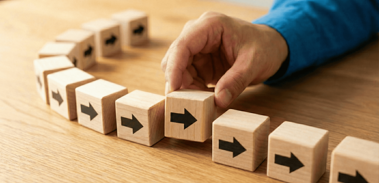 A hand placing a wooden block with a directional arrow into a sequence, illustrating how to use data to restart momentum and align corporate social responsibility (CSR) strategies.