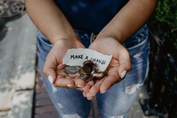 Hands holding coins and a note reading "Make a change"