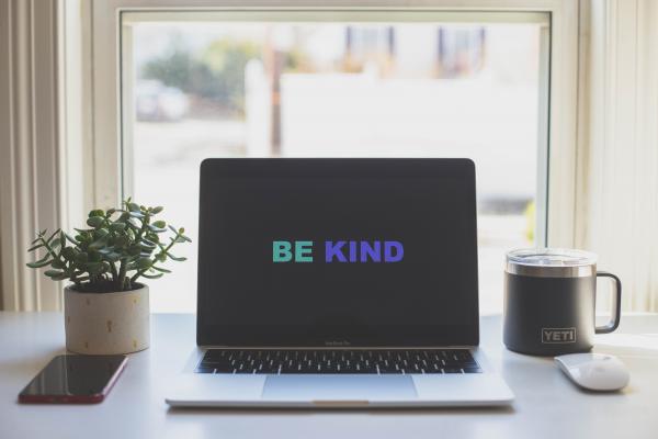 The words "Be Kind" are shown on a laptop screen.