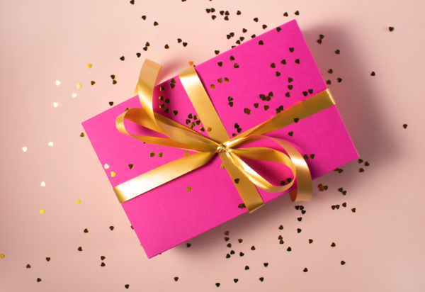 What is Corporate Donation Matching? (A gift is wrapped in pink paper, tied with gold ribbon and sprinkled with golden confetti)