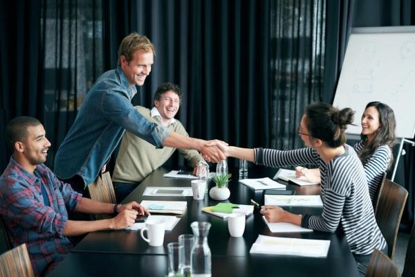 A nonprofit representative and a CSR manager shaking hands to form a grant partnership.